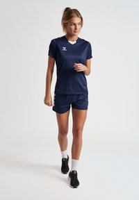 Marine atletikudstyrssæt med korte ærmer, fremstillet af letvægtsstof; har kontrasterende detaljer på shorts og logo ved brystet.