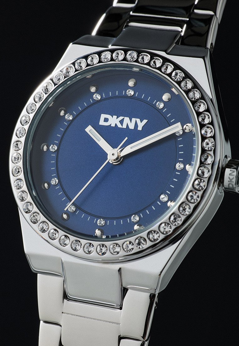 Orologio da polso DKNY argento con quadrante blu, marcatori delle ore in cristallo e bezels incastonati di cristalli che mostrano le 10:10:37.