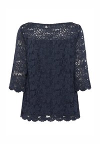 Top in pizzo blu navy con maniche a tre quarti, caratterizzato da un motivo floreale e orlo a onde. Tessuto leggero e semi-trasparente.