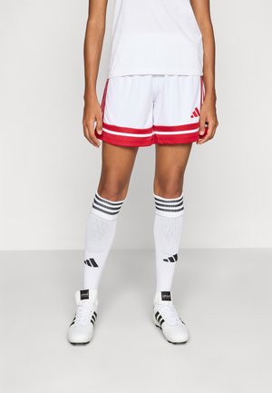 Witte sportshorts met rode accenten en drie rode strepen. Gepaarde met witte sokken met zwarte strepen en witte voetbalschoenen.