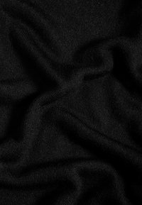 Tessuto a maglia nero con una texture morbida e liscia, caratterizzato da pieghe e grinze delicate, che mostra un colore uniforme senza modelli o accenti visibili.