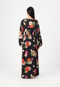 Blommig maxiklänning med långa ärmar, svart bakgrund, livfulla orange, rosa och gröna blommor, elastisk midja, flödande tyg och avslappnad passform.