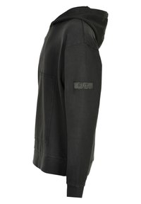 Svart huvtröja med ficka framtill och ribbade ärmar, med en lapp märkt "F.U.T." på vänster ärm. Tillverkad av texturerat tyg.