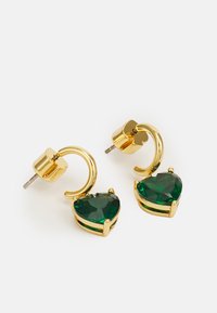 Χρυσά σκουλαρίκια με χρυσούς κρίκους που διαθέτουν καρδιοειδείς πράσινους πολύτιμους λίθους, κρατημένους σε ρύθμιση τεσσάρων δακτύλων. Απαλές, γυαλισμένες μεταλλικές λεπτομέρειες.