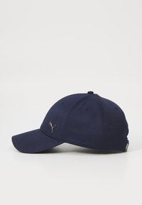 Navy blue cap made of fabric, featuring a curved brim, stitched detailing, and a metallic logo accent on the front left side.
