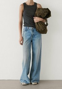 Top a coste grigio, jeans in denim blu larghi, borsa in tessuto verde oliva oversize, design minimalista. Texture lisce e vestibilità morbida.