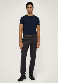 Námořnické bavlněné tričko s kulatým výstřihem v kombinaci s tmavě šedými slim-fit kalhotami. Hnědý kožený opasek a černé kotníkové boty doplňují outfit.