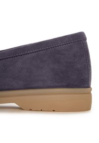 Chaussure à enfiler en daim gris foncé avec semelle en caoutchouc beige, surpiqûres visibles le long du bord supérieur et talon légèrement relevé.