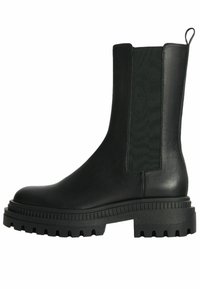 Botas de tobillo negras con paneles laterales elásticos, suela gruesa y parte superior de cuero suave. Presenta acentos texturizados y una lengüeta.