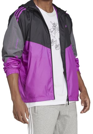 Lila und graue Windjacke mit Reißverschluss vorne, Kapuze und elastischen Bündchen. Verfügt über drei Streifen auf den Schultern und dezente Logodetails.