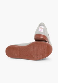 Lichtgrijze canvas schoenen met een rubberen, gestructureerde bruine zool. Heeft een label op de hiel met een berenlogo, met de tekst "Made in Spain."
