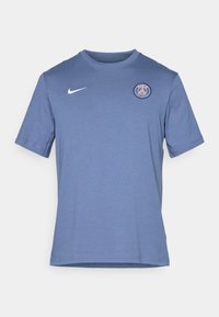 Kortærmet blå T-shirt lavet af en bomuldsblanding. Har et hvidt Nike-logo og et rundt Paris-logo på venstre bryst. Blød tekstur.