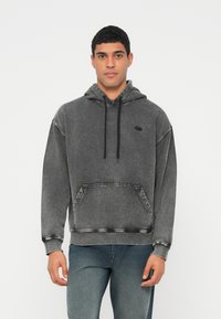 Γκρι, υπερμεγέθη φούτερ με τσέπη μπροστά, κουκούλα με κορδόνι και αντίθετη ραφή. Μαλακό, υφή ύφασμα με μικρό λογότυπο.