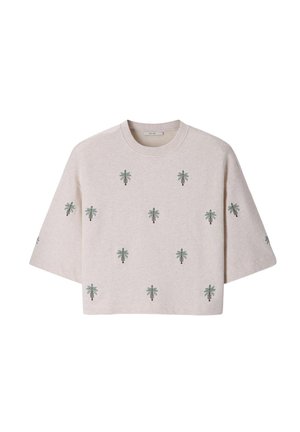 Pull beige clair à manches courtes avec des motifs de palmiers verts répartis uniformément sur le devant et les manches, avec un col rond.