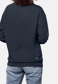 Mörkblå sweatshirt med avslappnad passform, med rund halsringning och ribbade muddar. Inkluderar en liten logotypdetalj på den nedre ryggen.