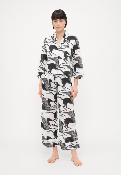 Σετ πιτζάμας μαύρου και άσπρου χρώματος από ελαφρύ ύφασμα, με έντονα animal prints. Το τοπ διαθέτει κολάρο με σχισμή και μπροστινή τσέπη, ενώ το παντελόνι είναι άνετο.