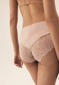 Light pink panties featuring a smooth fabric with lace trim, showcasing floral patterns and scalloped edges along the legs.