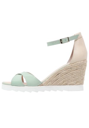 Sandalia de cuña de charol verde menta con tacón trenzado de yute, correa ajustable en el tobillo y suela blanca texturizada.