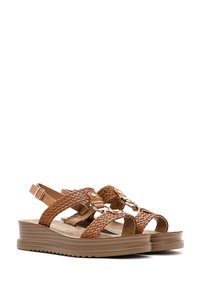 Sandalias de cuña marrones con tiras trenzadas, hebilla ajustable en el tobillo y suela texturizada. Diseño de plataforma para mayor altura.