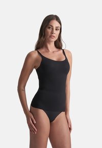 Černý top bez rukávů s tenkými ramínky, vyrobený z hladkého, elastického materiálu. Disponuje přiléhavým střihem a bezešvým spodním lemem pro maximální pohodlí.