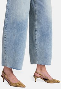 Sandały na obcasie z odkrytymi palcami w żółto-brązowy wzór wężowej skóry, z niskim obcasem typu kitten heel oraz wyraźnym paskiem wokół kostki.