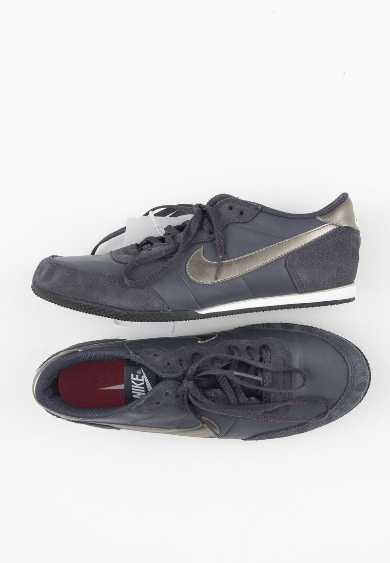 Nike tenisky z tmavě modré kůže s šedými semišovými detaily, s metalickým swooshem, zaoblenou špičkou a gumovou podrážkou.