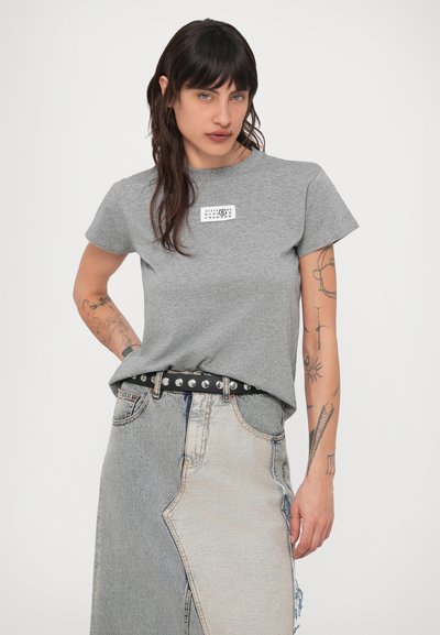 Grå bomull t-skjorte med korte ermer og en trykt logotagg. Brukes med et lappet av denimskjørt og et belte med nagler i svart.