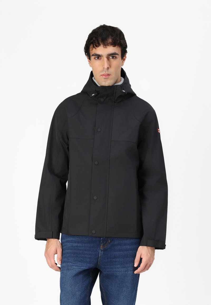 Μαύρο αδιάβροχο μπουφάν με κουκούλα, κλείσιμο με κόθρο και ραφές στους ώμους. Διαθέτει γκρεγ καλυμμένο εσωτερικό και λογότυπο στο μανίκι.