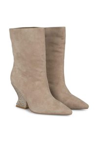 Bottines en suède beige avec un bout pointu et un talon en wedge décoré de strass. Texture lisse et silhouette ajustée.