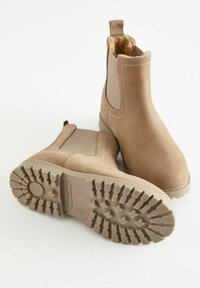 Bruna chelsea boots i mocka med elastiska sidopaneler, mjuk foder av päls och slitstark gummi-sula med mönster för grepp.