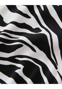 Tissu noir et blanc présentant un motif rayé zèbre, mettant en valeur une texture lisse et des rayures de largeur variable sur le matériau.