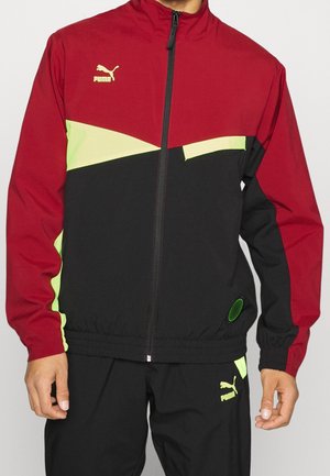 Chaqueta cortavientos en rojo, negro y verde neón, con cremallera frontal, cintura elástica y logo de Puma en el pecho y la manga.