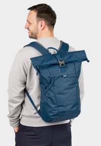 Navy roll-top backpack with a buckle closure, side pockets, and padded straps. Made of durable fabric with a smooth texture and lightweight design.