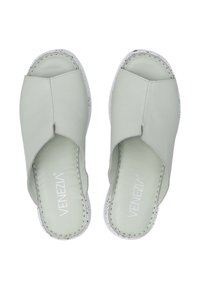 Lysgrønne læderslippers med krydsbåndsdesign, hvide såler og synlige syninger.