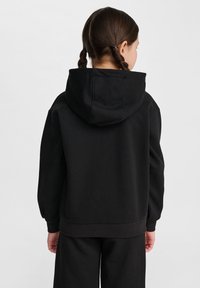 Czarna bluza z kapturem na sznurek, z prążkowanymi mankietami i dołem. Miły w dotyku materiał, prosty design, widok z tyłu. Spodnie w pasującym kolorze.