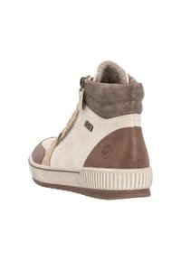 Zapatilla de media caña en cuero beige y marrón, con un diseño texturizado, cierre lateral con cremallera y suela de goma con surcos pronunciados.