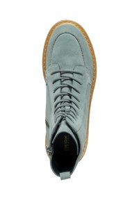 Sneaker a metà altezza in suede blu chiaro con una suola in gomma marrone, dotata di lacci frontali e una cerniera laterale per un accesso facile.