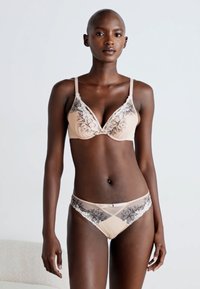 Beige lingerie set featuring floral lace accents, with a triangular bralette and matching briefs, both displaying sheer mesh detailing.