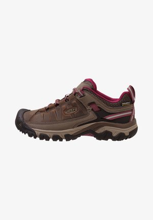 Zapatos de senderismo marrones y grises con acentos rojos, que cuentan con una suela de goma gruesa, una parte superior de cuero duradera y paneles de malla transpirable.