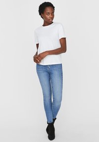 Witte katoenen t-shirt met een ronde halslijn, gecombineerd met lichtblauwe skinny jeans en zwarte enkellaarsjes, met een getailleerde pasvorm.