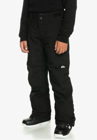 Čierne snehové nohavice vyrobené z odolného, vodeodolného materiálu. Obsahujú dve predné gombíky, úpravu pásu na suchý zips a detail loga.