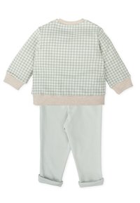 Sudadera a cuadros verdes con puños beige, combinada con pantalones verde menta claros con dobladillo enrollado. Material de algodón suave para mayor comodidad.