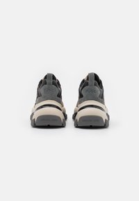 Sorte og taupe sneakers med ruskind og mesh teksturer, med en kraftig sål, bageste pull tab og indgraveret "MICHAEL KORS" branding.