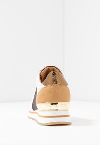 Bílé a hnědé tenisky s textured patou, zlatým akcentem a perforovanými detaily. Měkký materiál s polstrovanou podrážkou pro pohodlí.