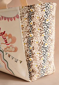 Auduma somiņa ar leoparda raksta sānu paneli un priekšējo paneli ar krāsainiem stendiem, mākoņiem un varavīksnes motīviem.