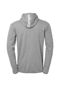Grå hættebluse med lange ærmer, løs pasform og et hvidt "Kempa" logo på ryggen. Blødt stof med en glat tekstur.