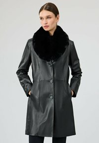 Czarny skórzany płaszcz z kołnierzem z sztucznego futra, zapięciem na guziki i bocznymi kieszeniami. Posiada wykończenia ze szwami oraz elegancki, dopasowany krój.