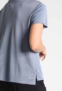 Blå kortärmad träningsskjorta med en strukturerad meshbakdel, rundad nederdel och sidofickor för ökad andningsförmåga och komfort.