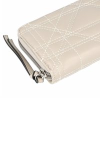 Beige leather wallet with diagonal quilted pattern, white stitching, and a zip closure. Features a black wrist strap attached.