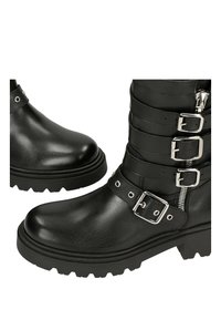 Černé kožené kotníkové boty s kulatou špičkou, několika kovovými sponami, zipy a texturovanou gumovou podrážkou pro lepší přilnavost.